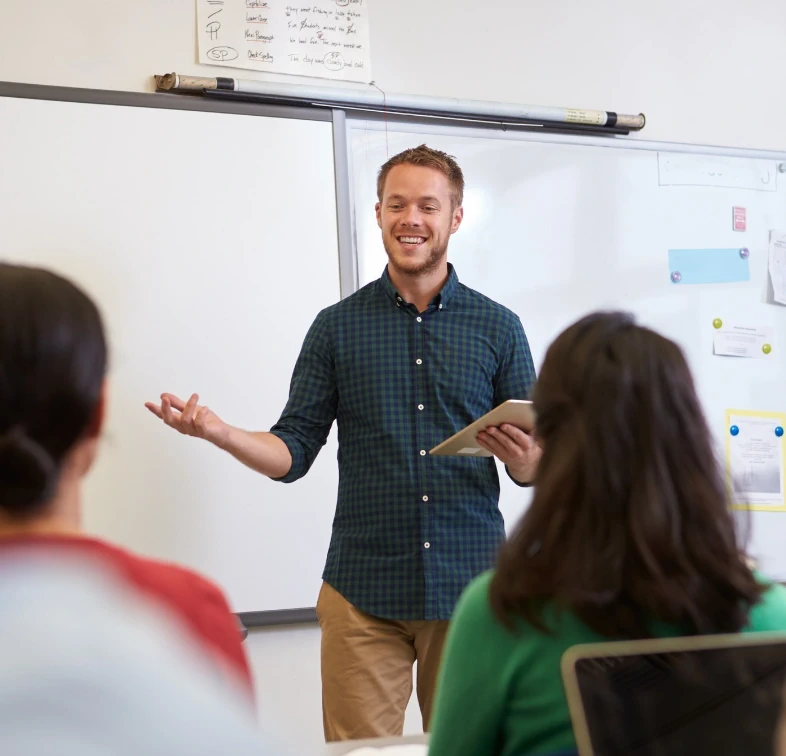Male teacher stood at the front of a secondary school class