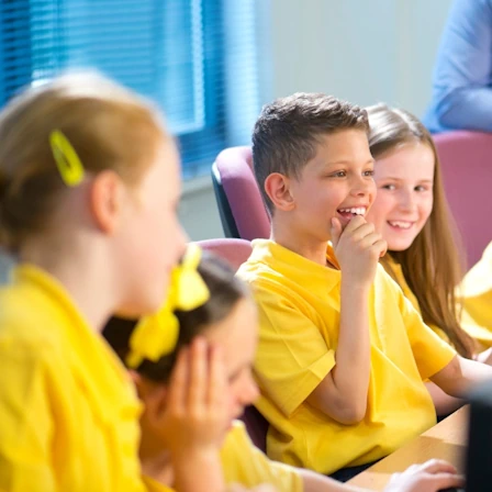 Primary school students in yellow polo shirts during an IT lesson